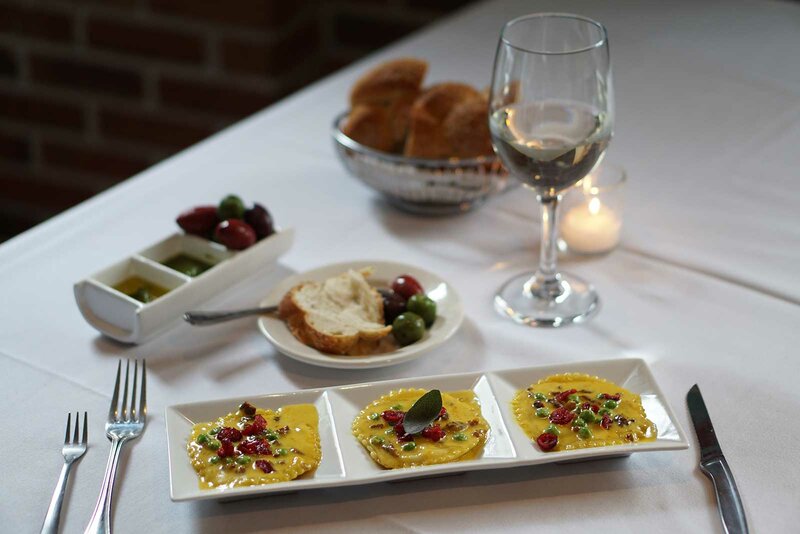 Ravioli with plated bread, olives, olive oil with glass of wine