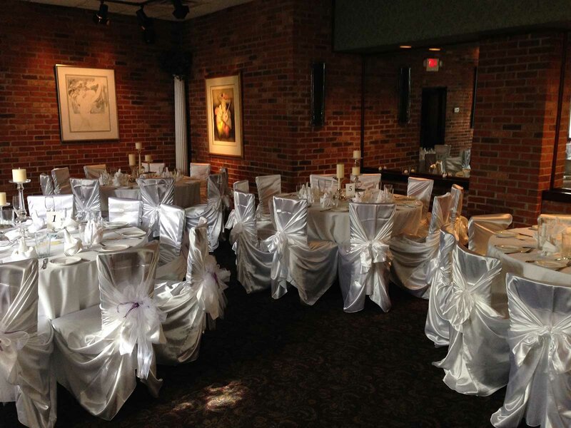 Dining room set for private event with silver chairs and table cloths