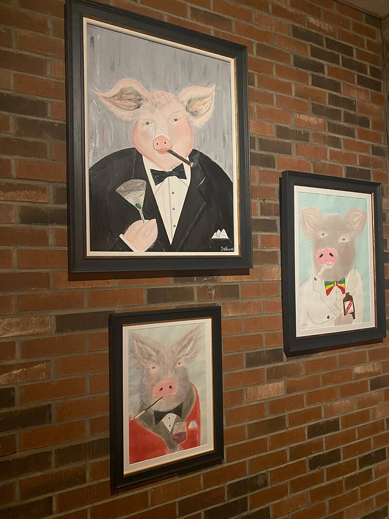 Three paintings of pigs in suits hanging on wall